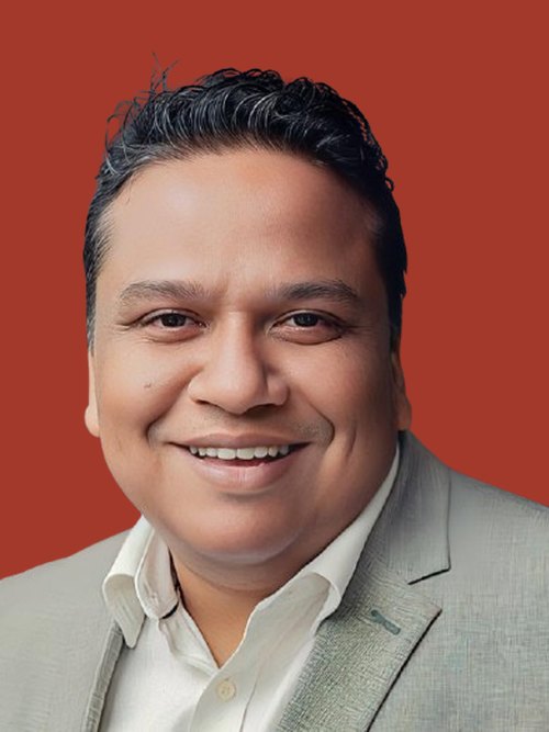 Kazi Mohiuddin smiling, in a light grey blazer